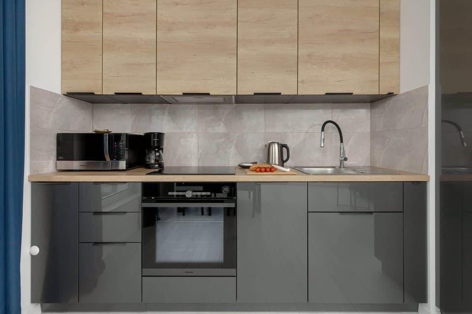 A modern kitchen featuring wooden cabinets, black appliances, and a sleek design.