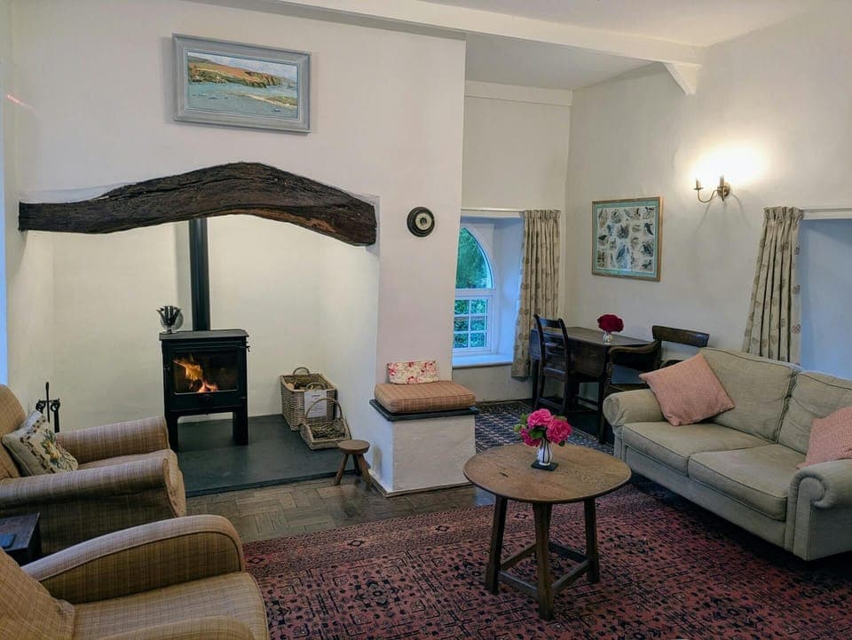 Living room with an inglenook fireplace; sofa, armchairs, coffee table and log burner