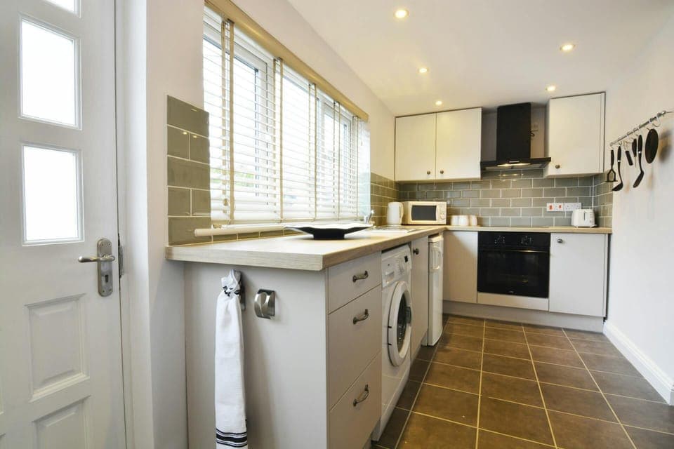 Kitchen with cooker, cooker hood, sink, washing machine, microwave, kettle and toaster