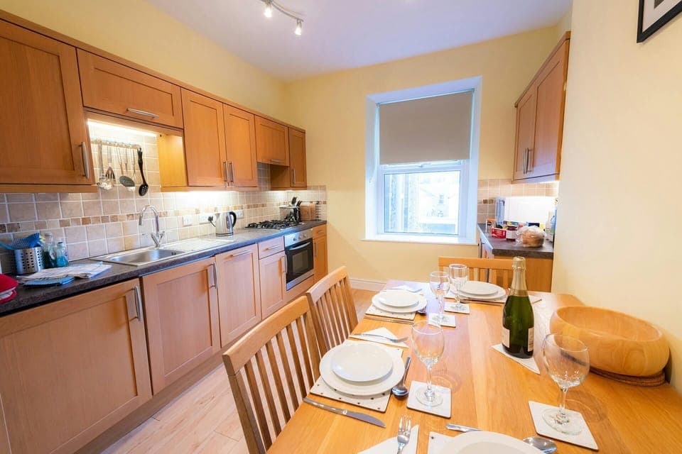 Fitted kitchen with electric cooker, extractor hood, microwave, kettle, dining table with chairs