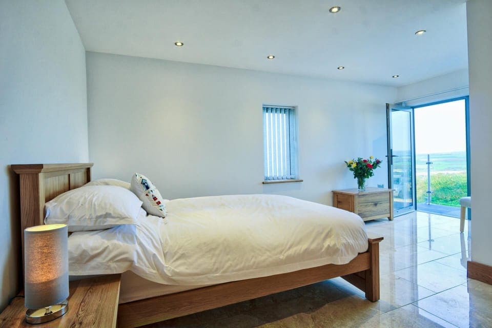 Ground floor bedroom with double bed and open patio doors to slate terrace, countryside beyond