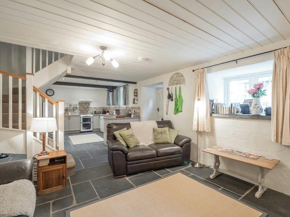 Living area and kitchen, stairs to first floor: sofa, low table, floor lamp, small unit with lamp