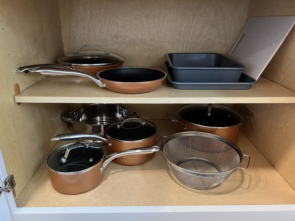 Pots, pans, colanders, baking trays, and cutting board in kitchen
