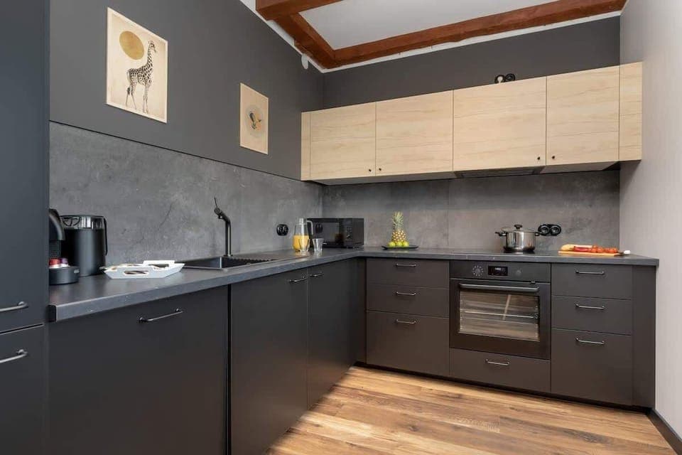 Modern kitchen with black cabinets, built-in appliances and brick wall accents.