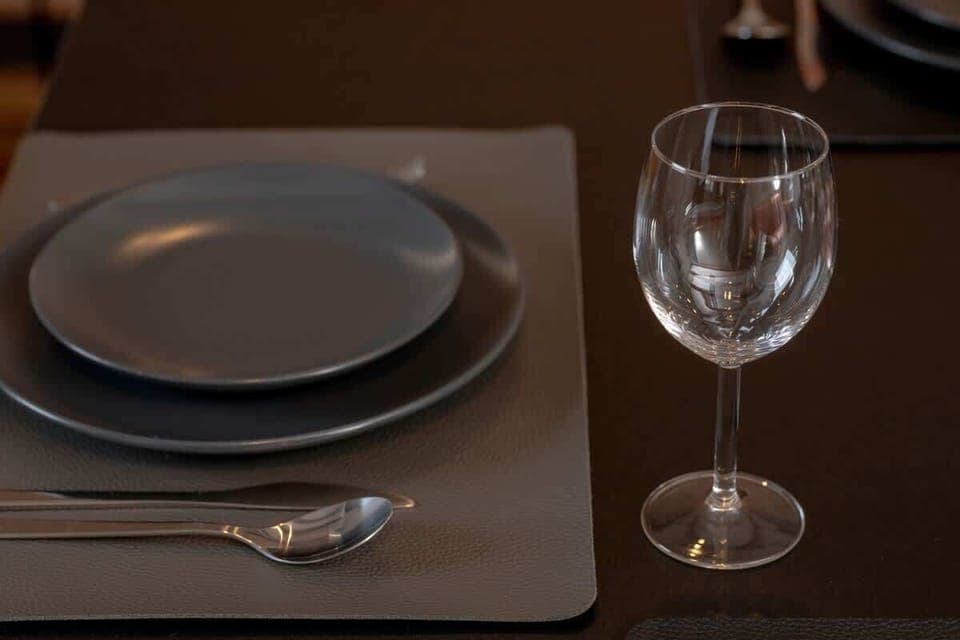 Sophisticated close-up of a dining setting with a black plate and a wine glass.
