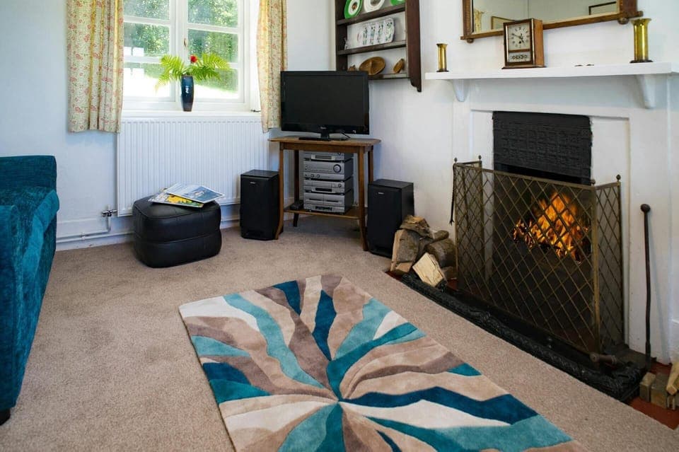Open fire in the living room in Garden Cottage, TV and window