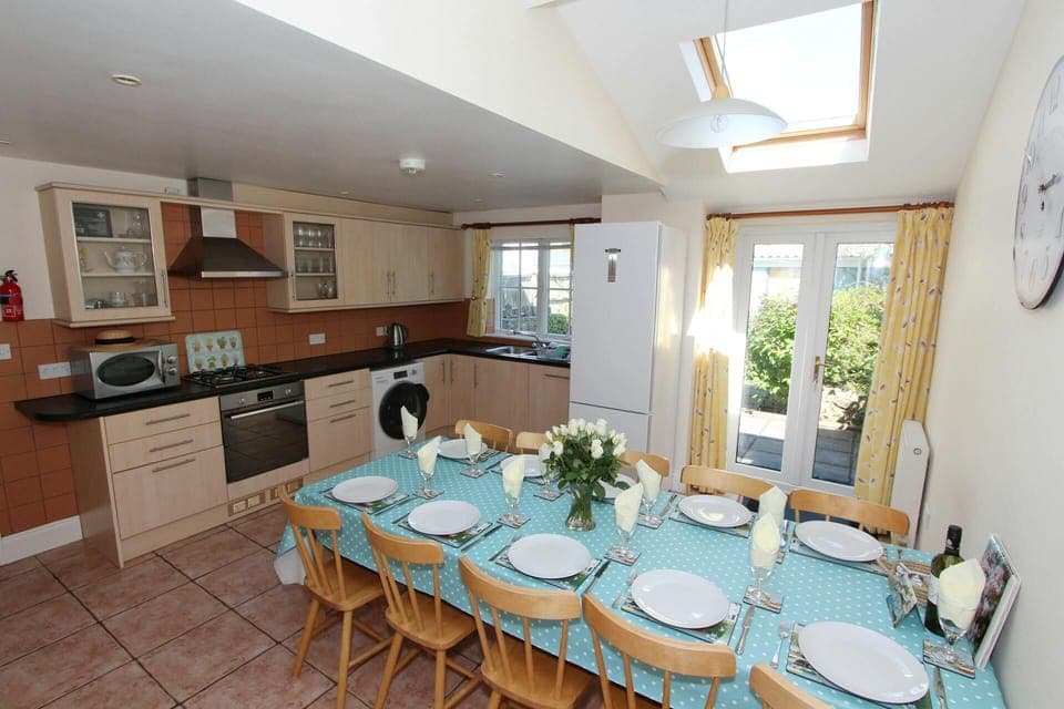 Fitted kitchen/dining area: oven, gas hob, microwave, kettle: dining table with ten chairs