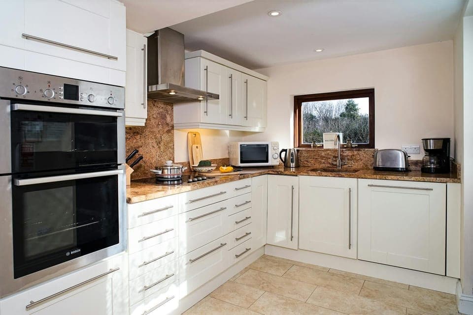 Kitchen at Glandwr with oven, microwave, kettle and kitchen equipment, tiled floor