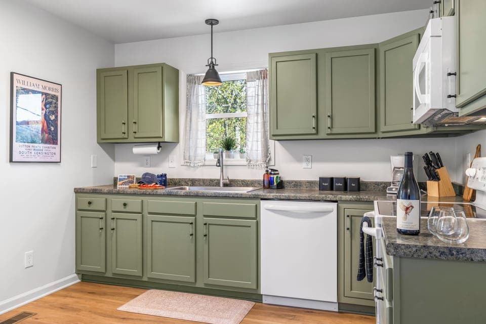 Fully equipped kitchen with stove, dishwasher, and bold matcha cabinets.