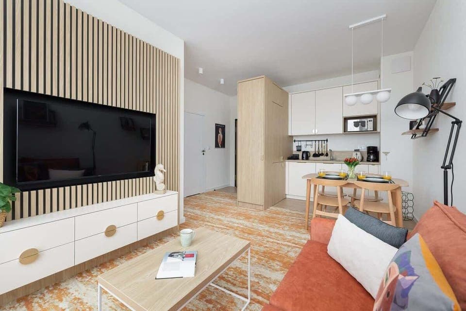 A modern living room with a wall-mounted flat-screen TV, built-in cabinetry, and a sofa facing a minimalist coffee table.