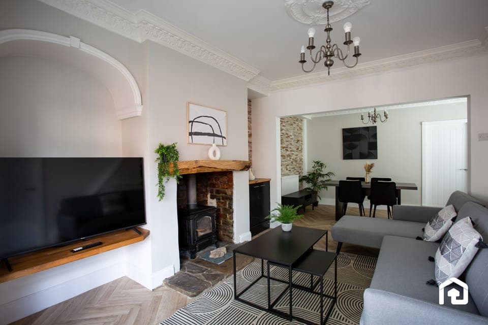 Elegant living and dining space with a cozy fireplace, modern furnishings, and a large TV. Stylish, spacious, and inviting.