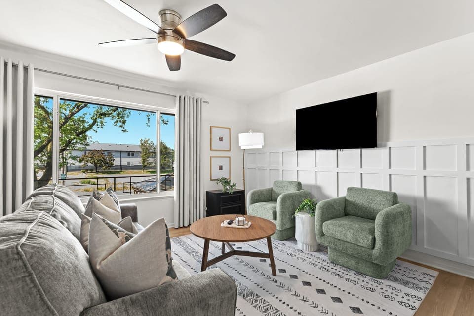 Bright and airy living space with large windows, cozy furniture, and direct views of the backyard greenery.