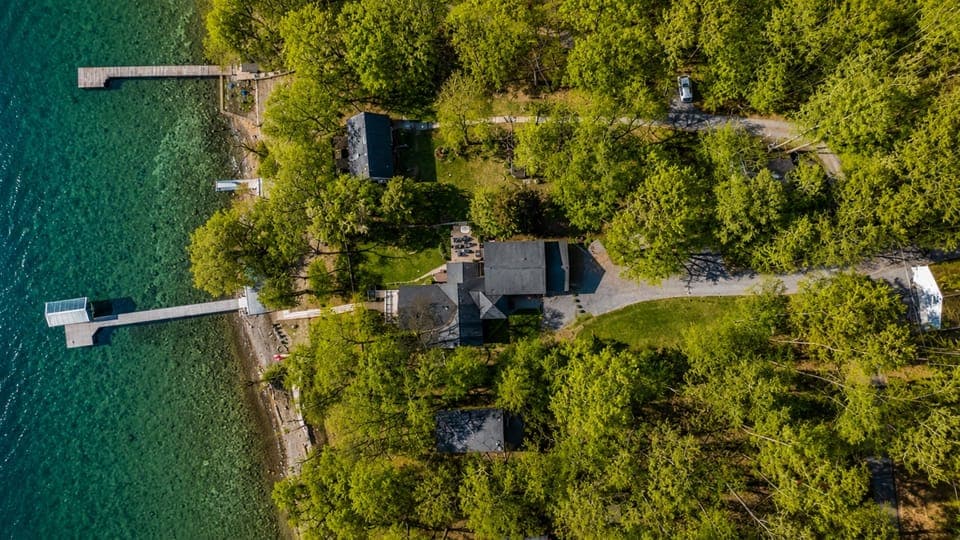 Discover the breathtaking layout of this lakeside retreat, captured from above. It features multiple cabins and private docks nestled among trees, perfect for both adventure and relaxation. 