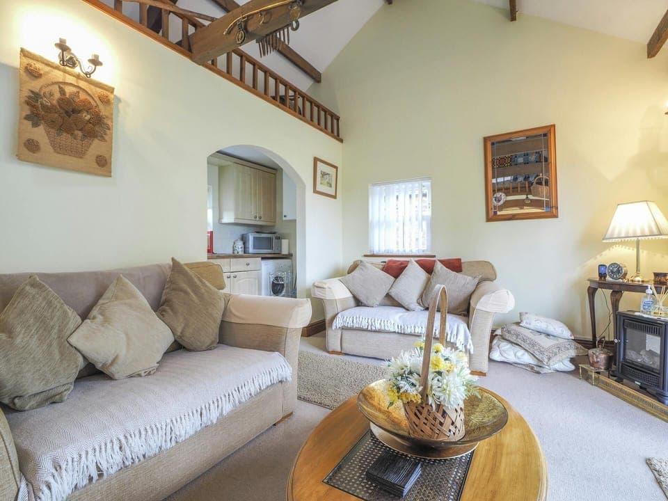 Living room with Gallery bedroom above; two sofas, coffee table, electric fire, table and lamp