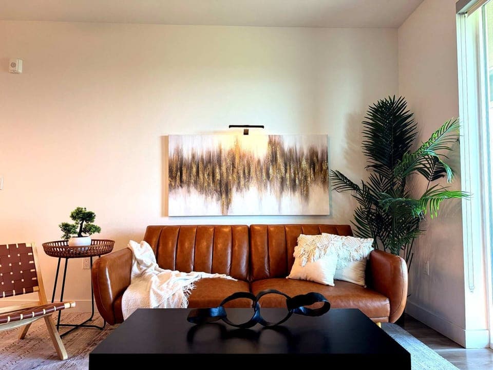 Spacious living room featuring a cozy sofa, two stylish armchairs, a full-size air mattress, and a 65" Smart TV with preloaded access to Netflix, Hulu, and Disney+, all set up for your enjoyment.