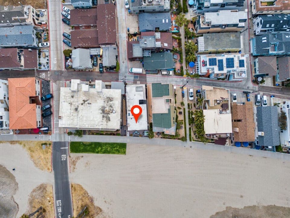 Overhead view of a beachside neighborhood, highlighting a prime property located just steps away from the sandy shoreline. The home`s proximity to the beach provides the perfect blend of convenience and coastal living, offering easy access to the ocean an