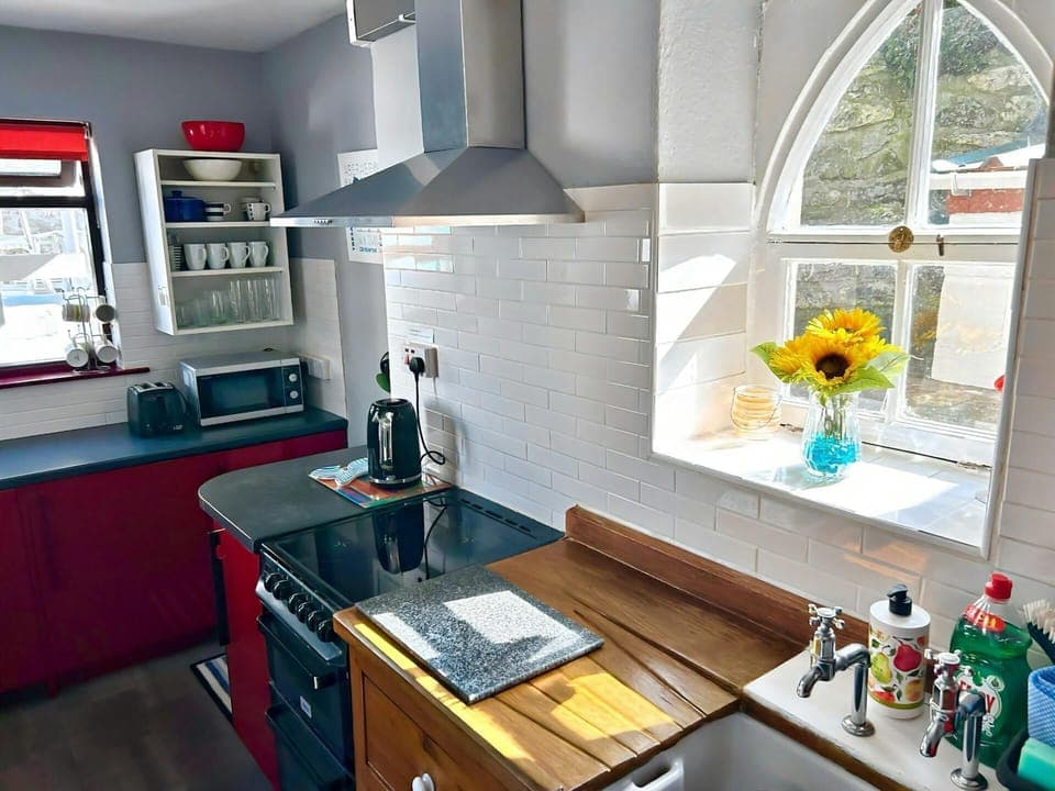 Kitchen with sink, cooker, kettle, toaster, microwave and arch window