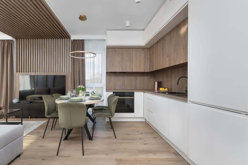 A spacious living room with light furniture and a large window overlooking the balcony invites relaxation in natural light.