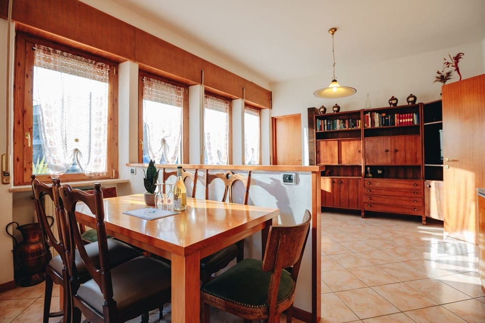 Spacious, bright dining room with wooden furnishings and large windows, perfect for sharing family meals in the apartment in Peschiera del Garda.