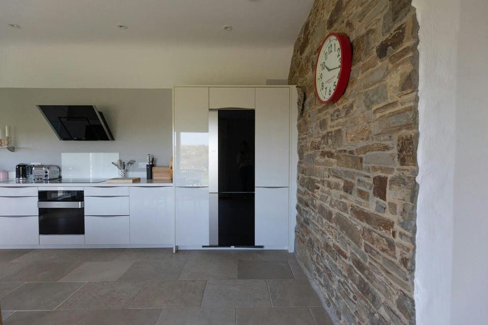 Kitchen with white gloss base cupboards. Electric cooker and extractor hood, fridge, kettle and toaster