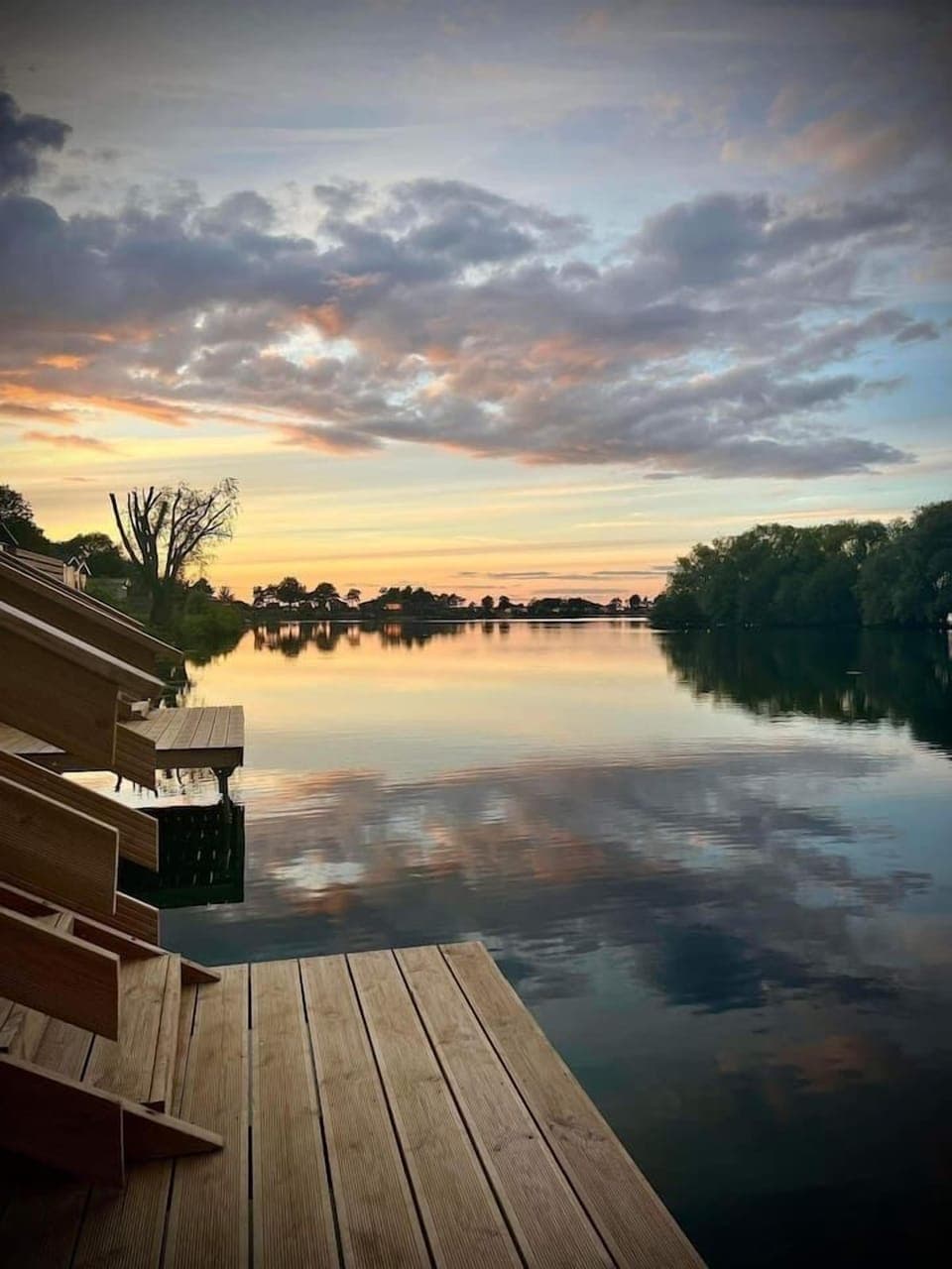 A breathtaking sunrise paints the sky with vibrant hues as it reflects on the calm waters of the lake, creating a magical spectacle from the lower jetty.
