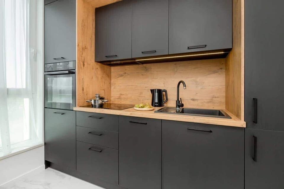 A kitchenette with black cabinets and a wooden worktop. The whole creates the perfect space for preparing home-cooked meals. 