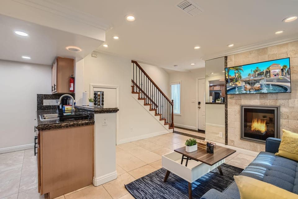 Sophisticated living room design with a sofa that opens up to full-size beds, 55” Smart TV,  office/kitchen seating, beautiful decor, and much more.