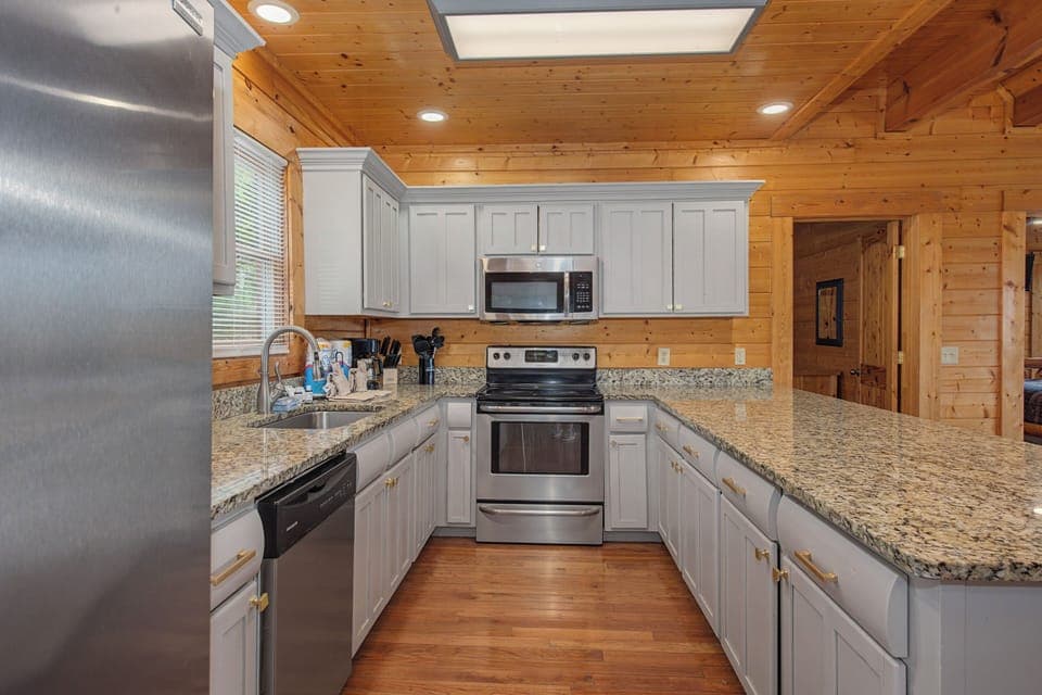 Your fully equipped kitchen awaits with granite counters, stainless steel appliances, and warm wood beams overhead for memorable meal prep.