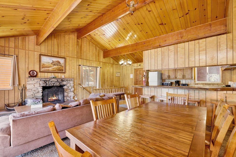 Warm living space featuring inviting sofa set, glowing hearth, and airy connection to kitchen