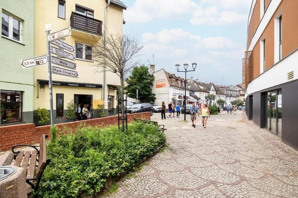 A view of a cobblestone street lined with shops and trees. Perfect for a leisurely walk in the neighborhood.