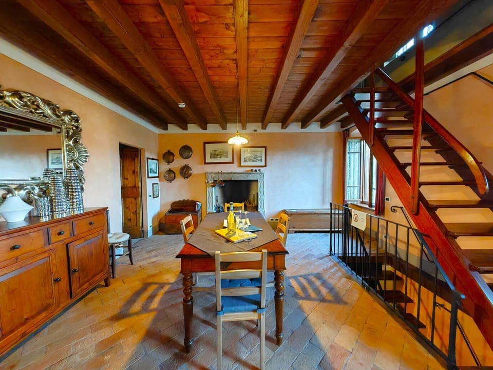 Charming rustic-style dining room with exposed beams and fireplace, perfect for sharing convivial moments in the apartment in Monzambano.