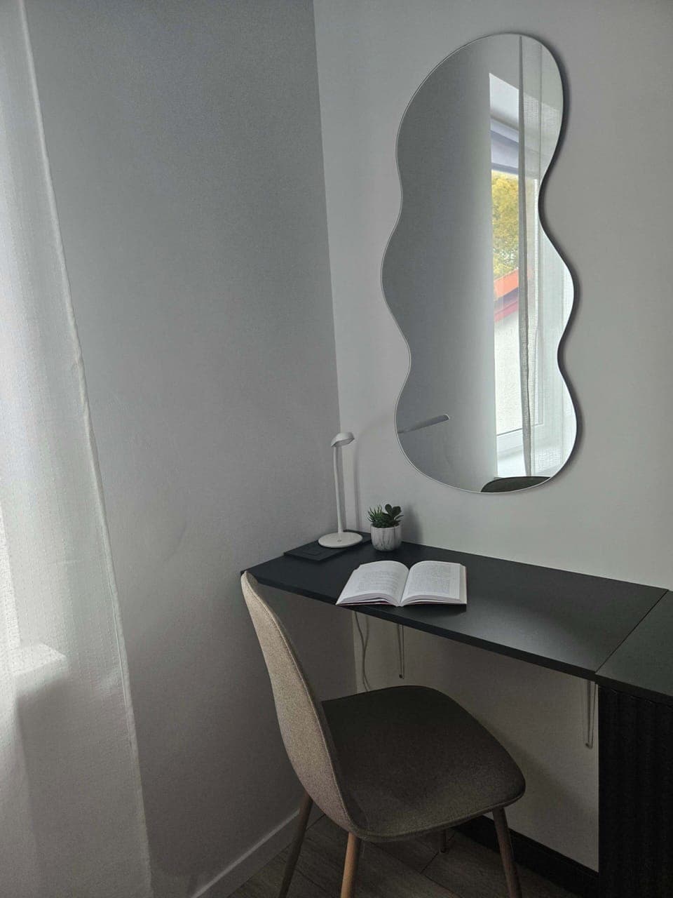 Comfortable desk with chair and decorative mirror on the wall.