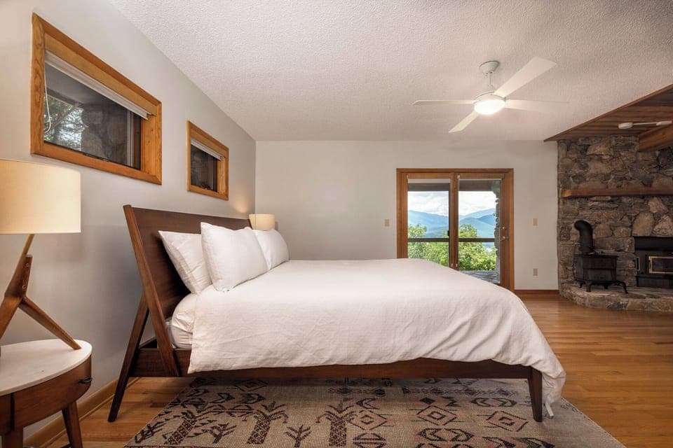 Lower-level primary suite with king-size bed, gas log fireplace, 55" Smart TV, en suite bathroom, and access to the lower level deck