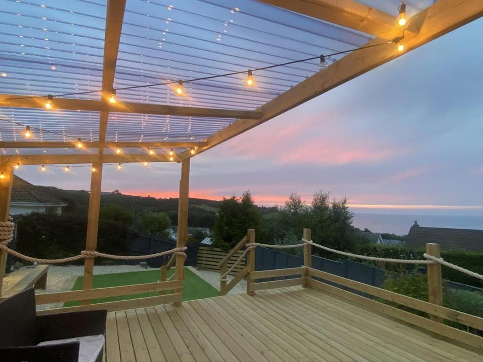 Deck area with festoon lights and sunset in the distance