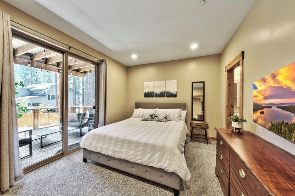 Bedroom 2 on 1st floor with queen bed, sliding glass door to balcony, and HDTV
