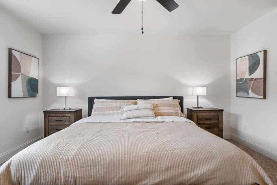 The main bedroom features a large king bed with ample linens, two nightstands with lamps that double as phone chargers, an 8-drawer dresser, a full-length mirror, and a closet with a luggage rack holder.