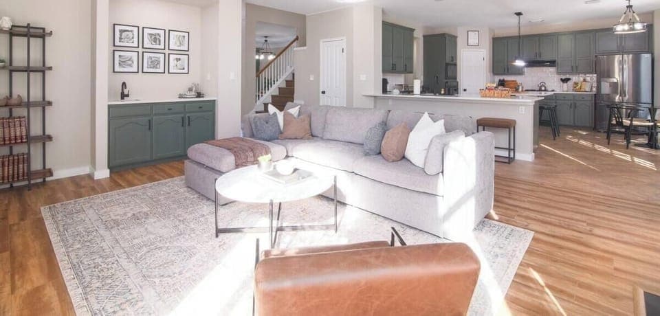 This modern living room boasts comfortable sofas and a stylish table, creating the perfect setting for afternoon teas or casual gatherings. The wooden floors add warmth and character, complementing the room's sleek, contemporary design.