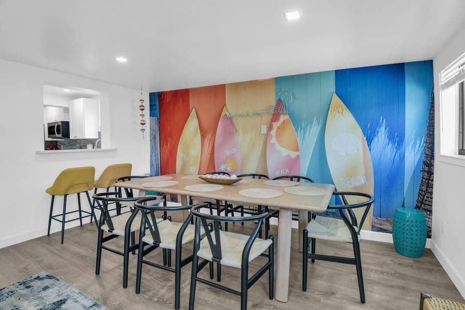 Gather around this spacious 8-seater dining table, where a vibrant surfboard wall mural adds a fun, coastal vibe to your mealtime experience.