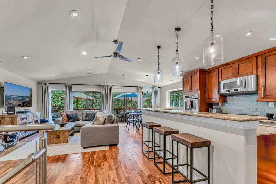 Main Living Space: upper floor, open layout, inviting living room with 65” smart TV, well-equipped kitchen, 6-person dining table, access to deck