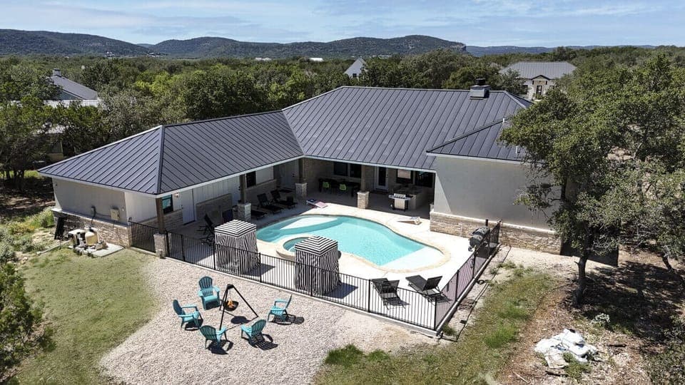 A bird`s-eye view of the property showcasing a relaxing pool, hot tub, and fire pit area, perfect for outdoor fun with family or friends.