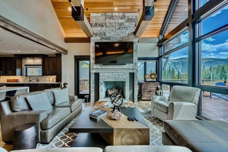 Relax in this spacious living room with beautiful mountain views, a cozy fireplace, and comfortable seating, creating the perfect family-friendly space for unwinding together.