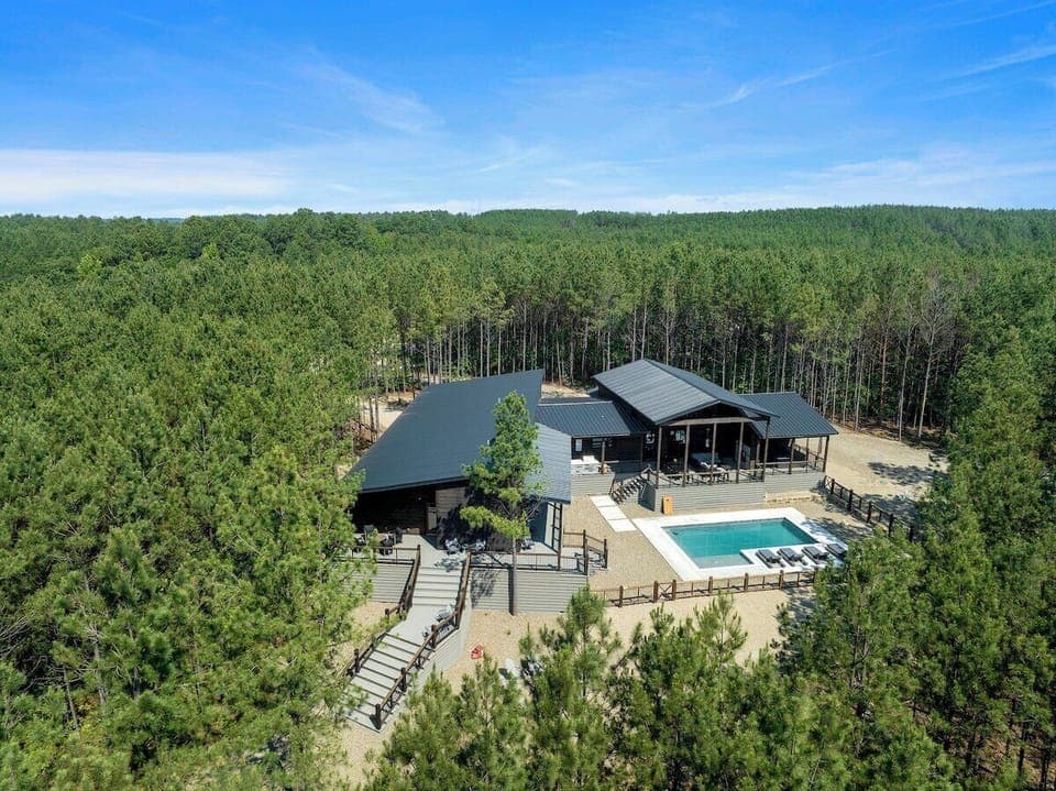 Secluded forest cabin with modern design, private pool, multiple decks, and lush tree surroundings.