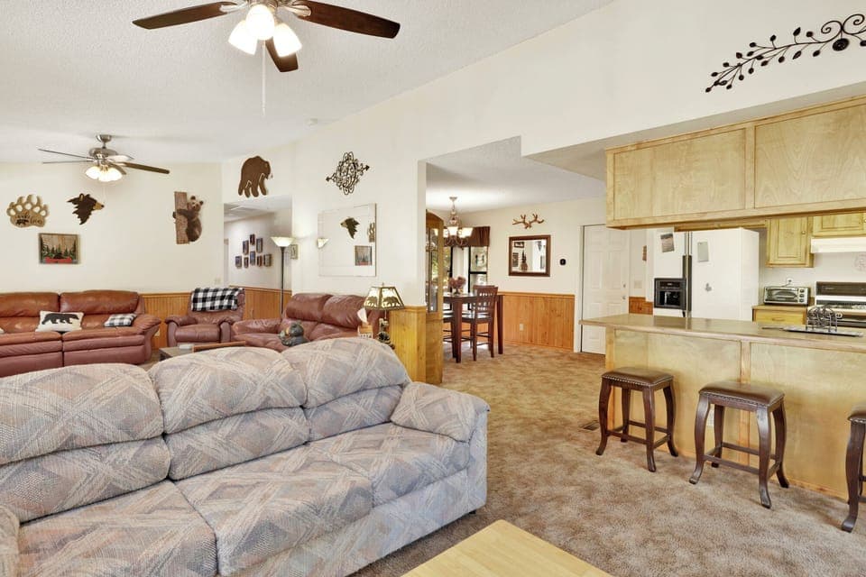 Cozy mountain living room with a stone fireplace, comfy seating, and smart TV—perfect for relaxing evenings, movie nights, and warm cabin vibes after outdoor adventures.