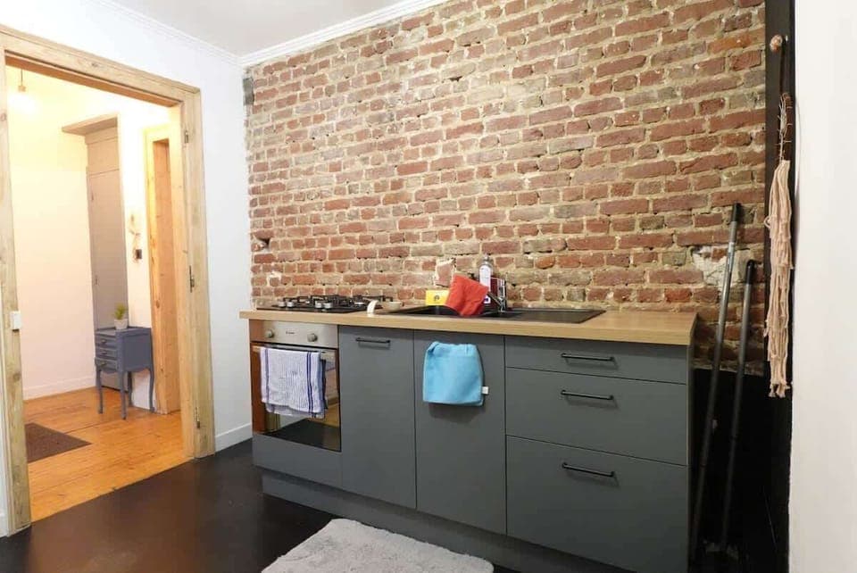 Cuisine semi ouverte équipée avec four, gazinière, bouilloire, cafetière et réfrigérateur avec congélateur.