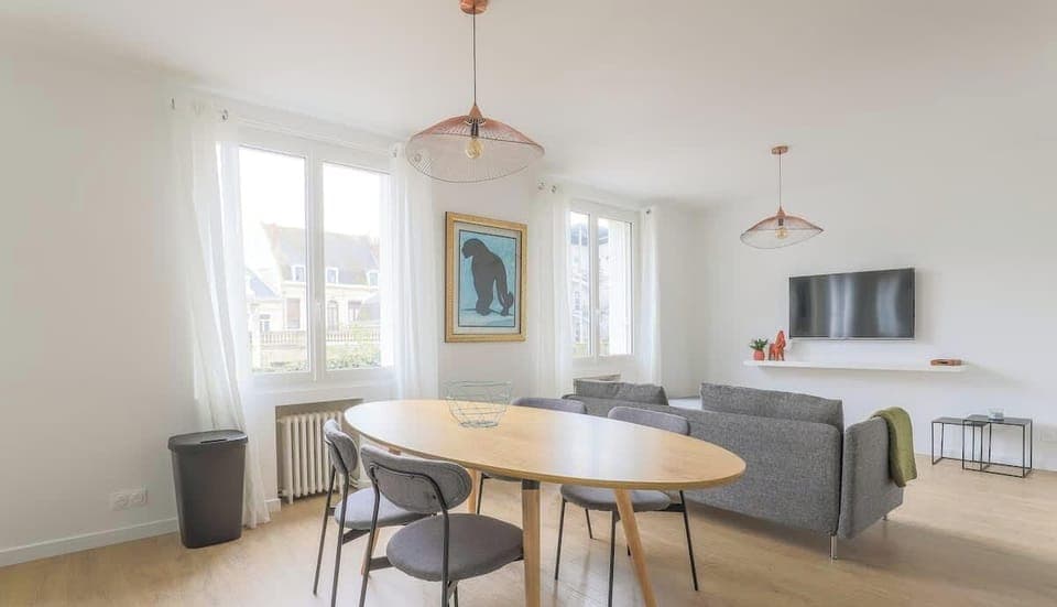 Salon avec TV HD et espace salle-à-manger, ouvert sur la cuisine.