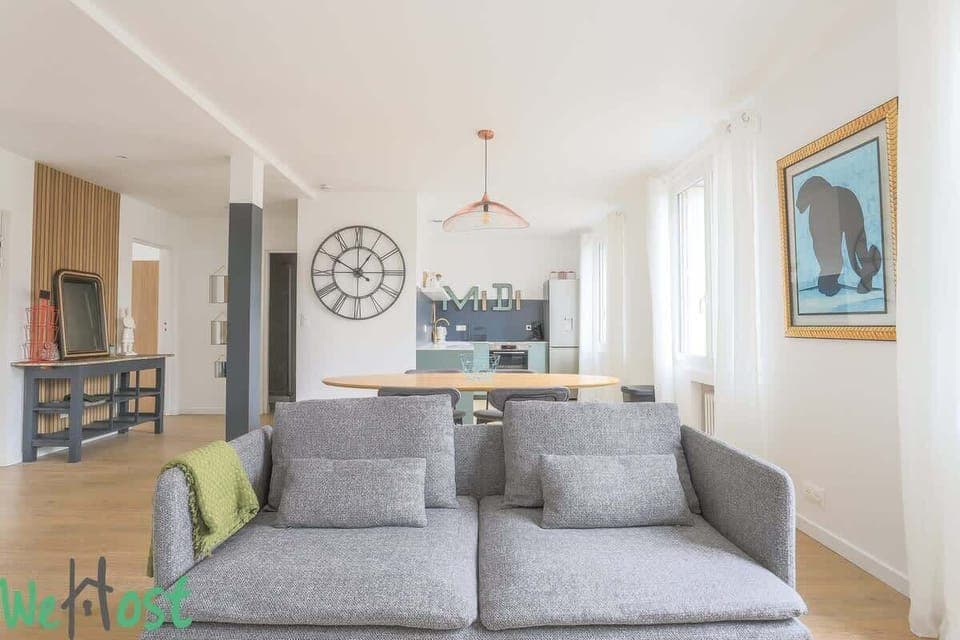 Salon avec TV HD et espace salle-à-manger, ouvert sur la cuisine.