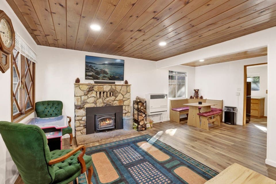 Cozy mountain living room with a stone fireplace, comfy seating, and smart TV—perfect for relaxing evenings, movie nights, and warm cabin vibes after outdoor adventures.