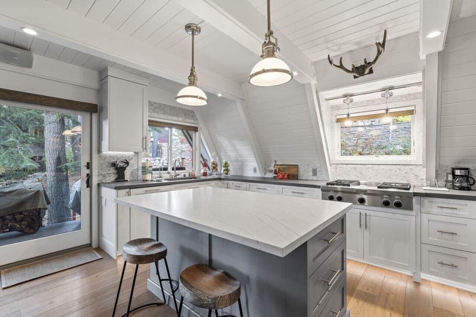 Modern A-frame cabin kitchen with a spacious island, stainless steel appliances, and rustic accents.