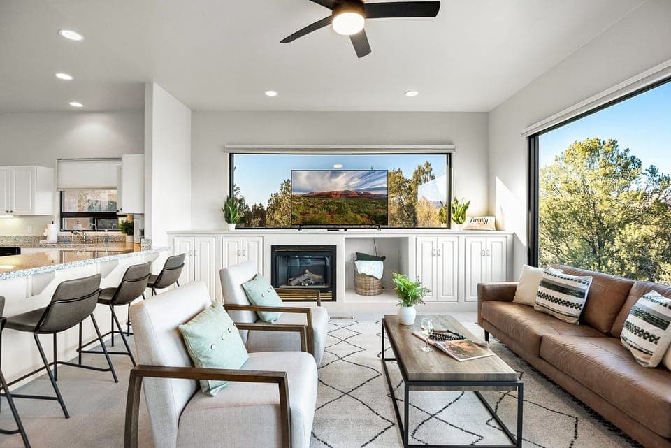 Living room with leather sofa, two chairs, open to kitchen and breakfast nook. Reflective 360 red rock view