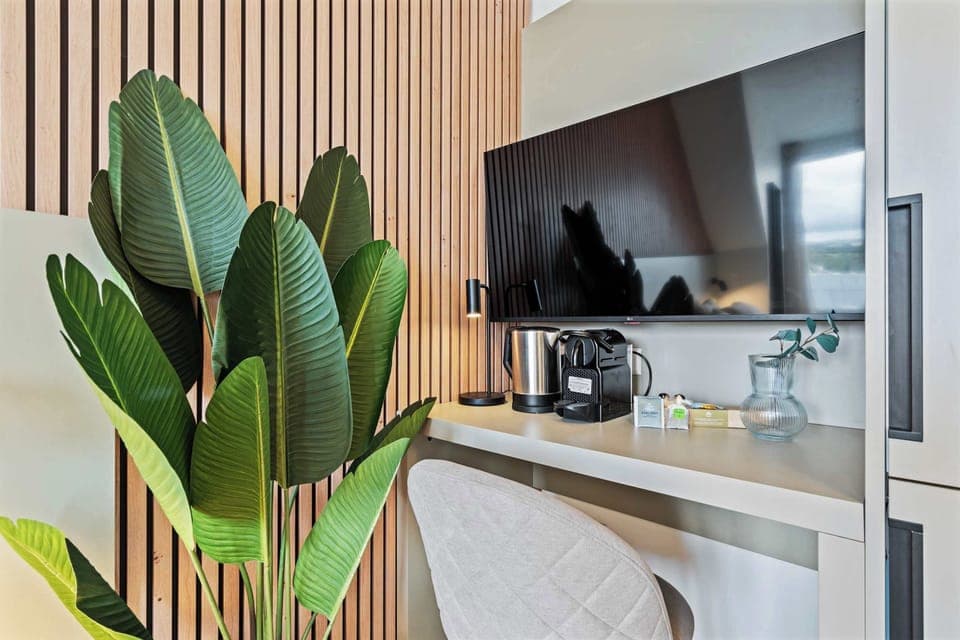 Functional Workspace and Entertainment Area – Wall-mounted TV, small desk, and a cozy chair create a perfect blend of comfort and productivity.